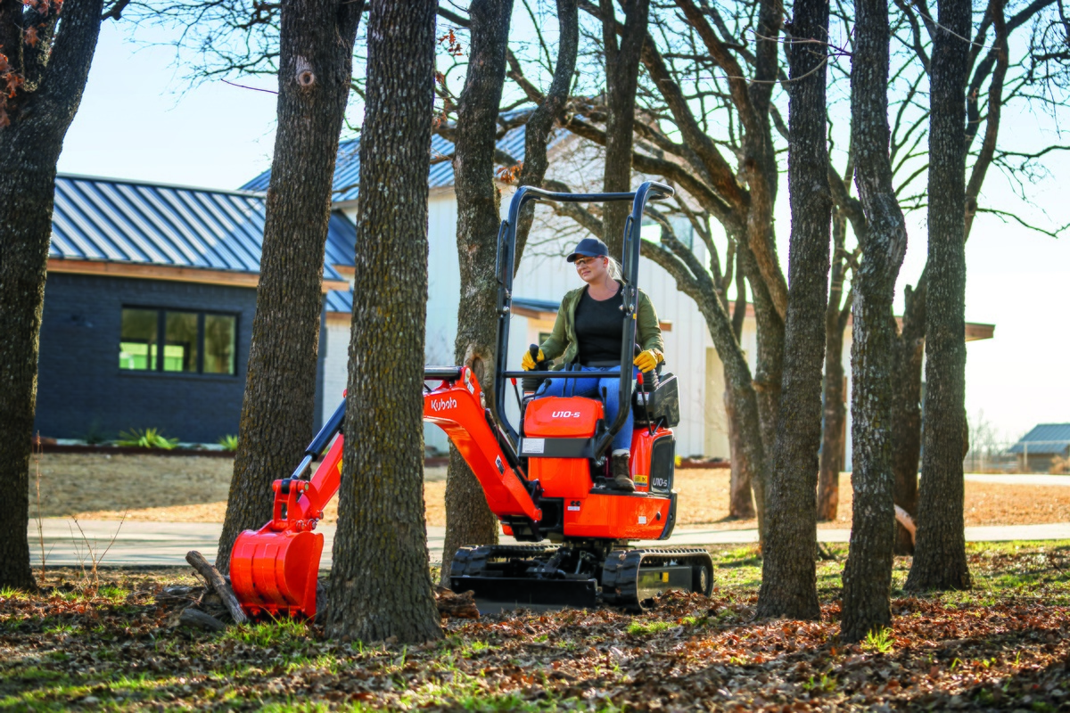 A woman picks up a log with a Kubota U10-5